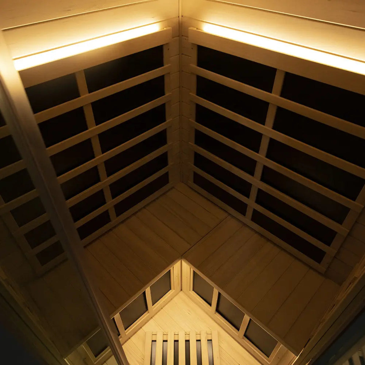 Interior view of a corner infrared sauna for 2-3 people featuring wooden panels and overhead lighting.