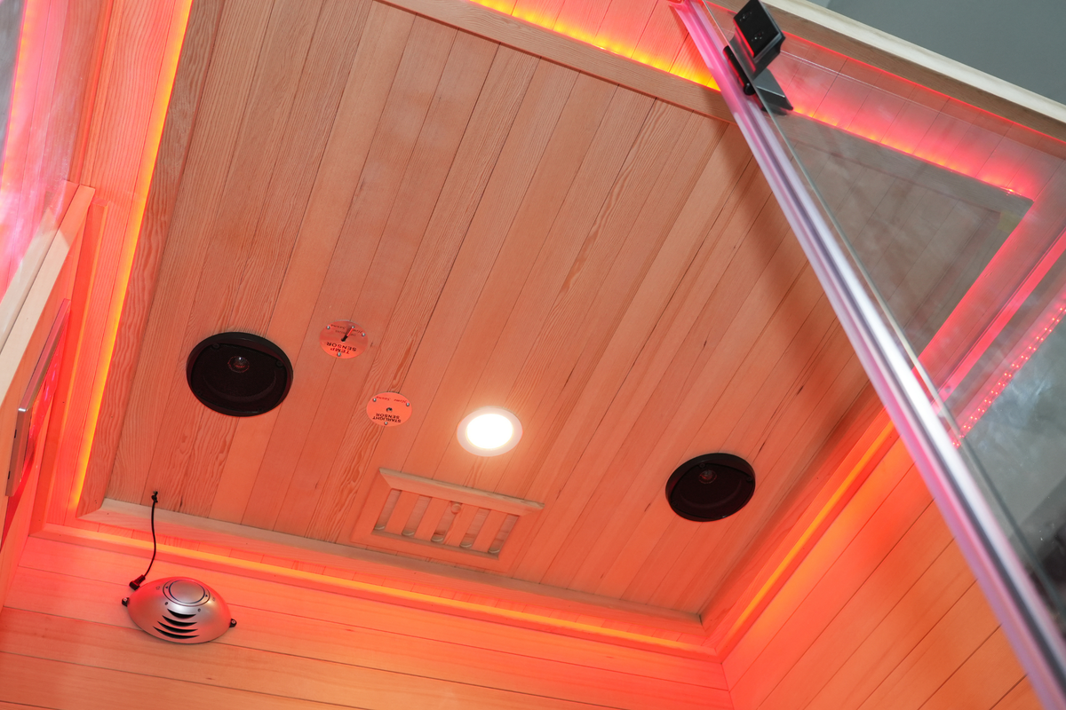 Interior view of a full spectrum infrared sauna featuring red light therapy lights and audio speakers.