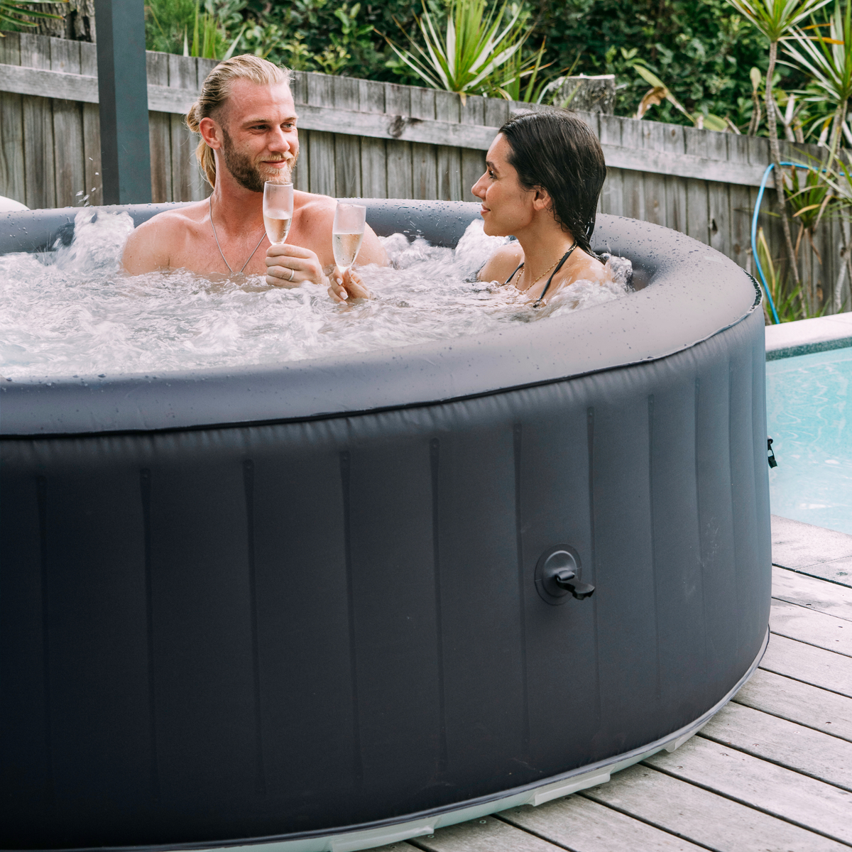 Two people in an inflatable hot tub outdoors