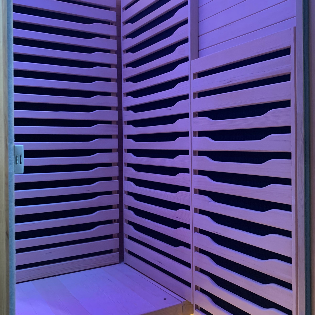 Interior view of a Full Spectrum Indoor Sauna featuring sleek wooden slats and ambient lighting.
