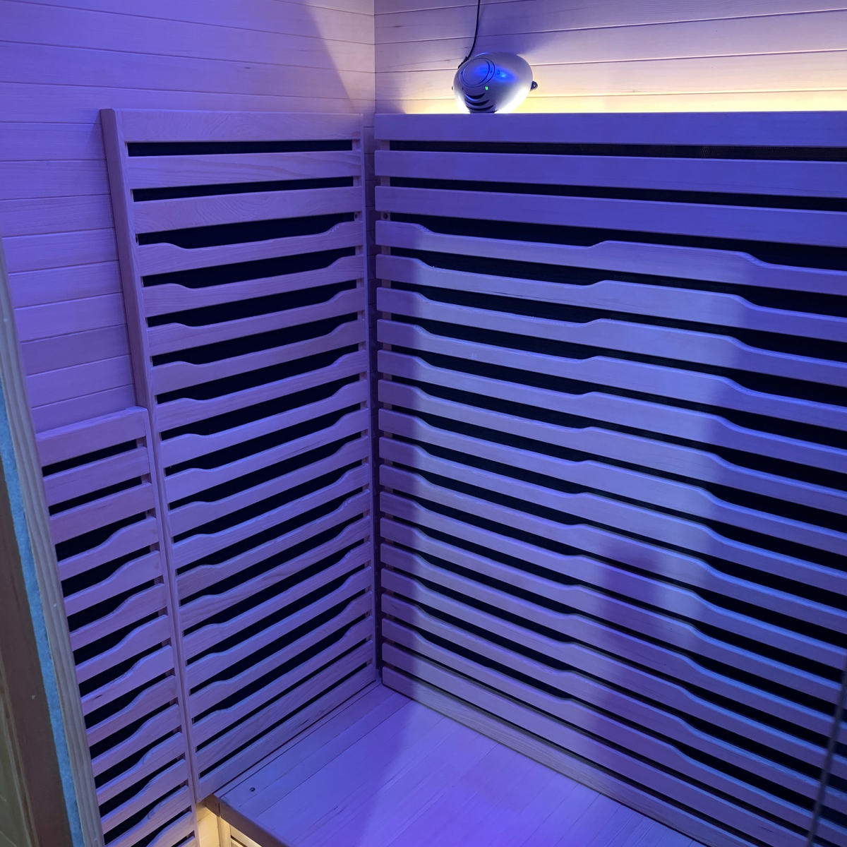 Interior view of a Full Spectrum Indoor Sauna featuring wooden slats and soft ambient lighting.