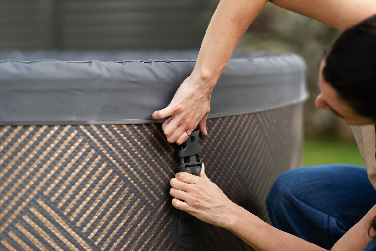 Person adjusting a connector on a rigid hot tub, showcasing the detailed design and user-friendly features.