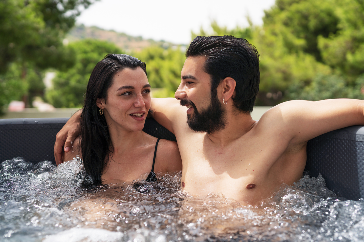 Couple enjoying time together in a rigid hot tub surrounded by greenery, relaxing in the warm water.