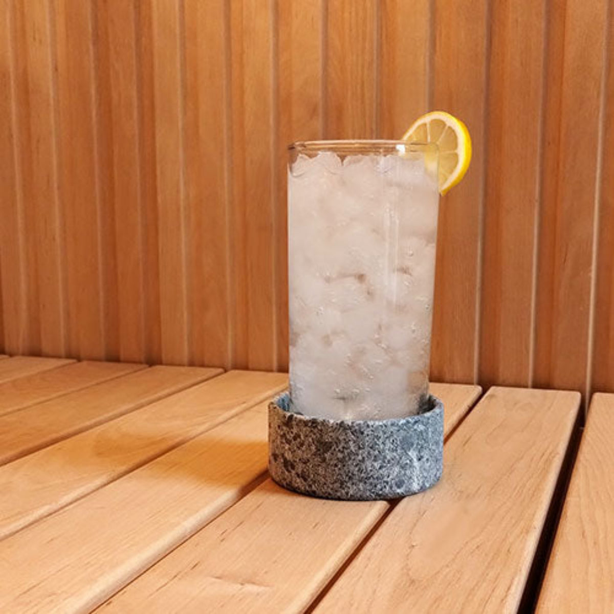 Highball glass with lemon wedge on a wooden surface in a SaunaLife Coaster or Aroma Tray