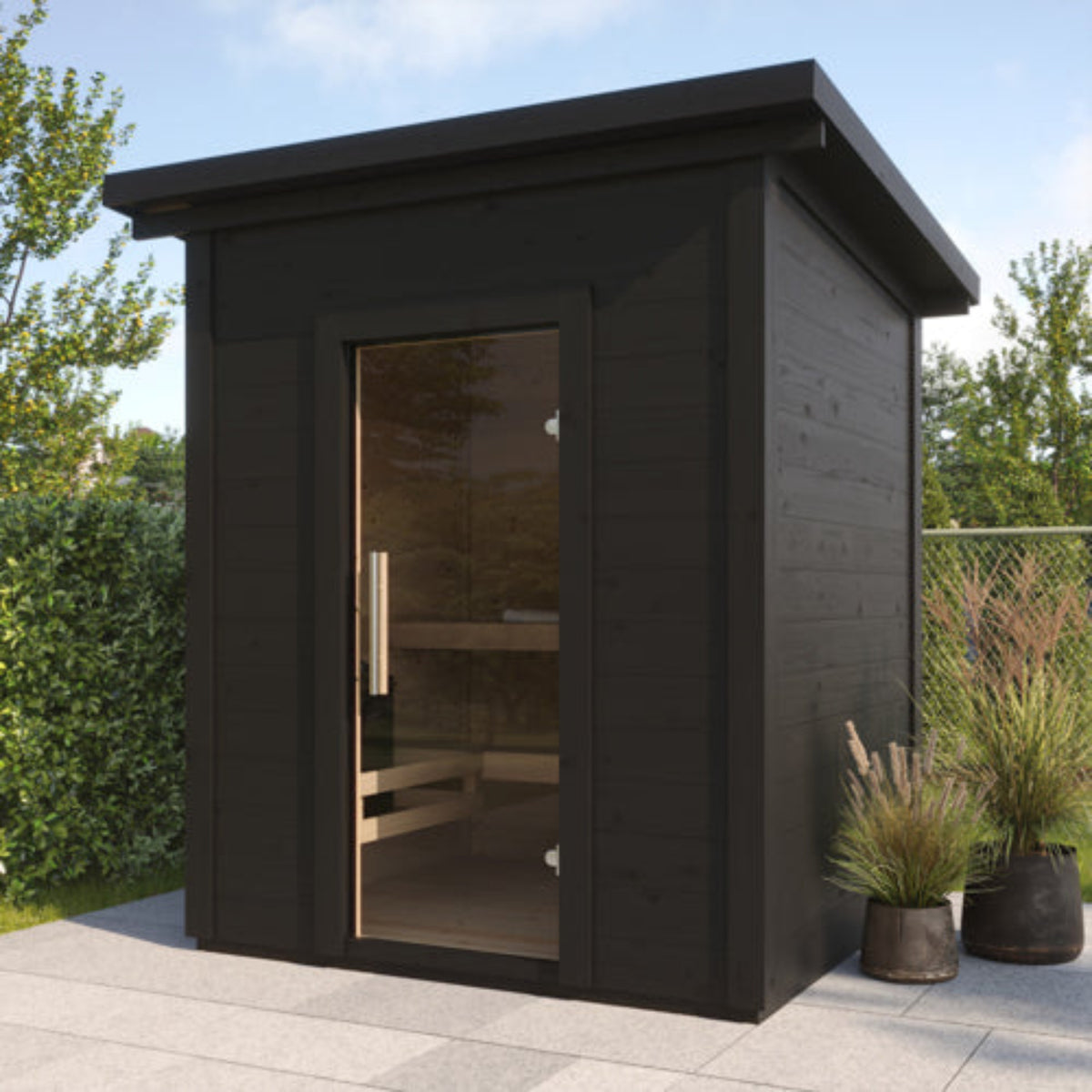 SaunaLife Garden-Series Model G2B Outdoor Garden Saunawith a glass door and visible wooden interior benches, shown on a paved patio with garden plants and trees in the background.