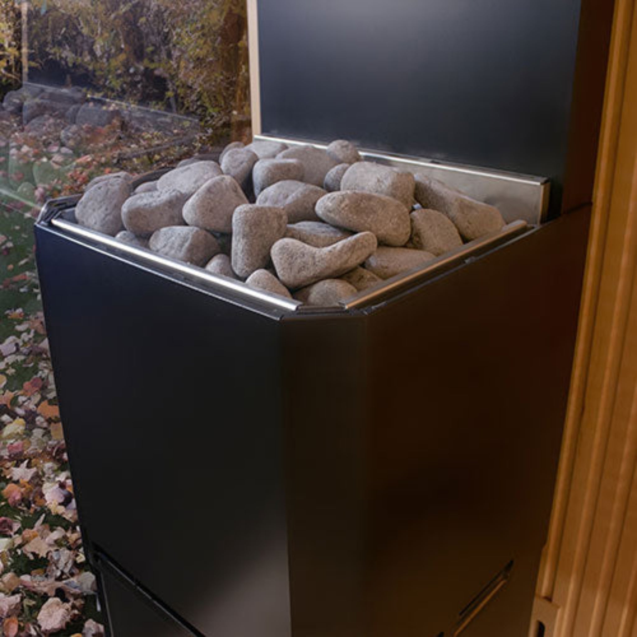 Black Saunum Air L Sauna Heater with stones by a sauna window in a backyard setting