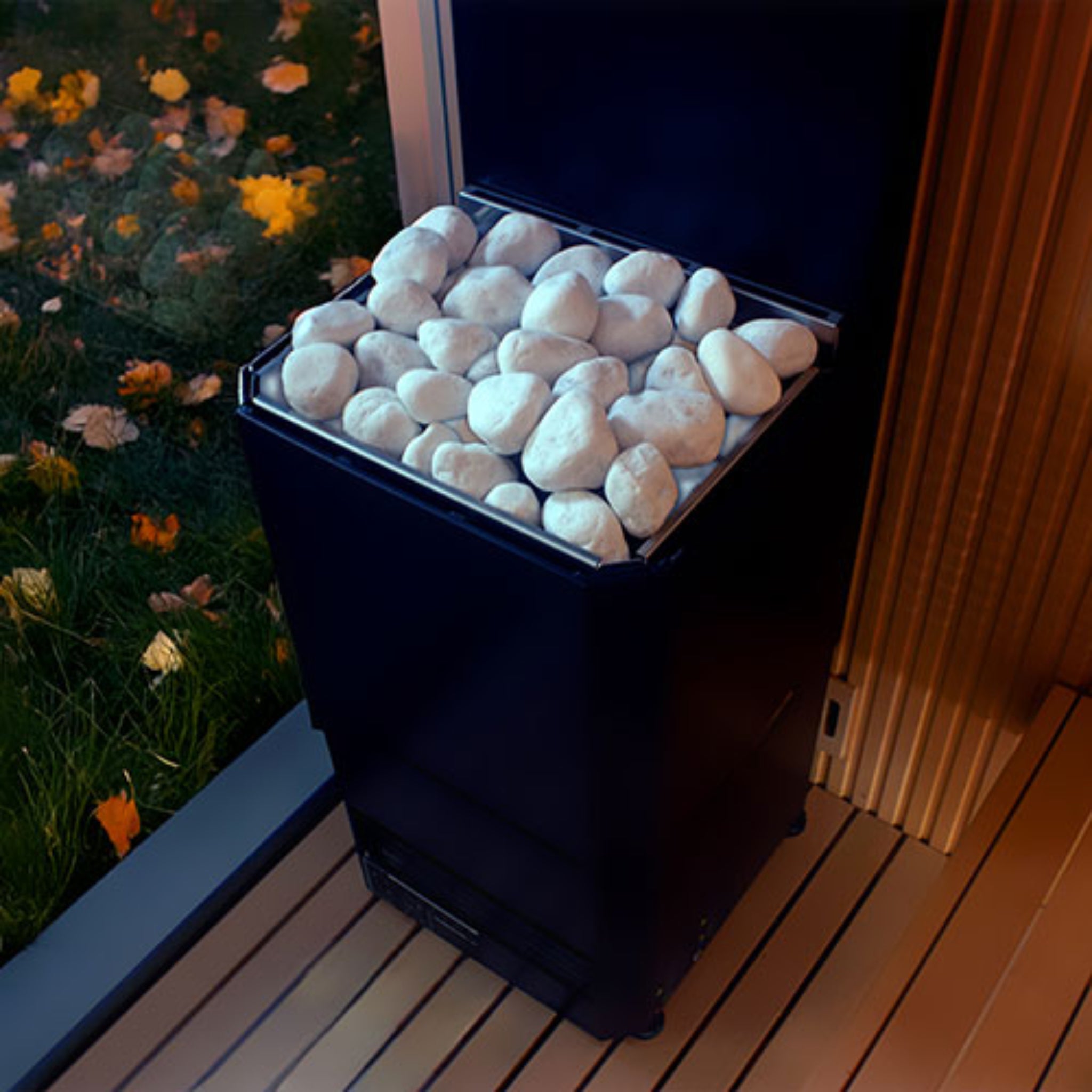 Black Saunum Air L Sauna Heater - by a sauna window in a backyard setting with white stones inside.