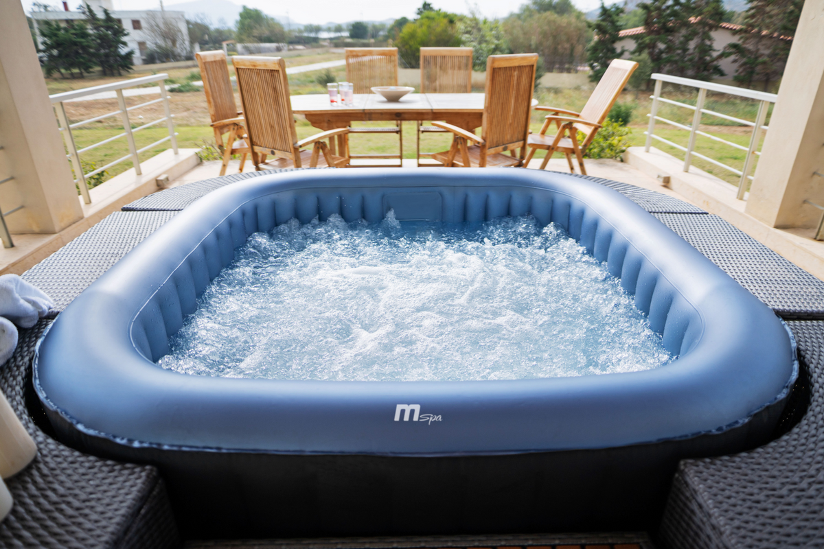 Inflatable hot tub on a patio with chairs and a table in the background
