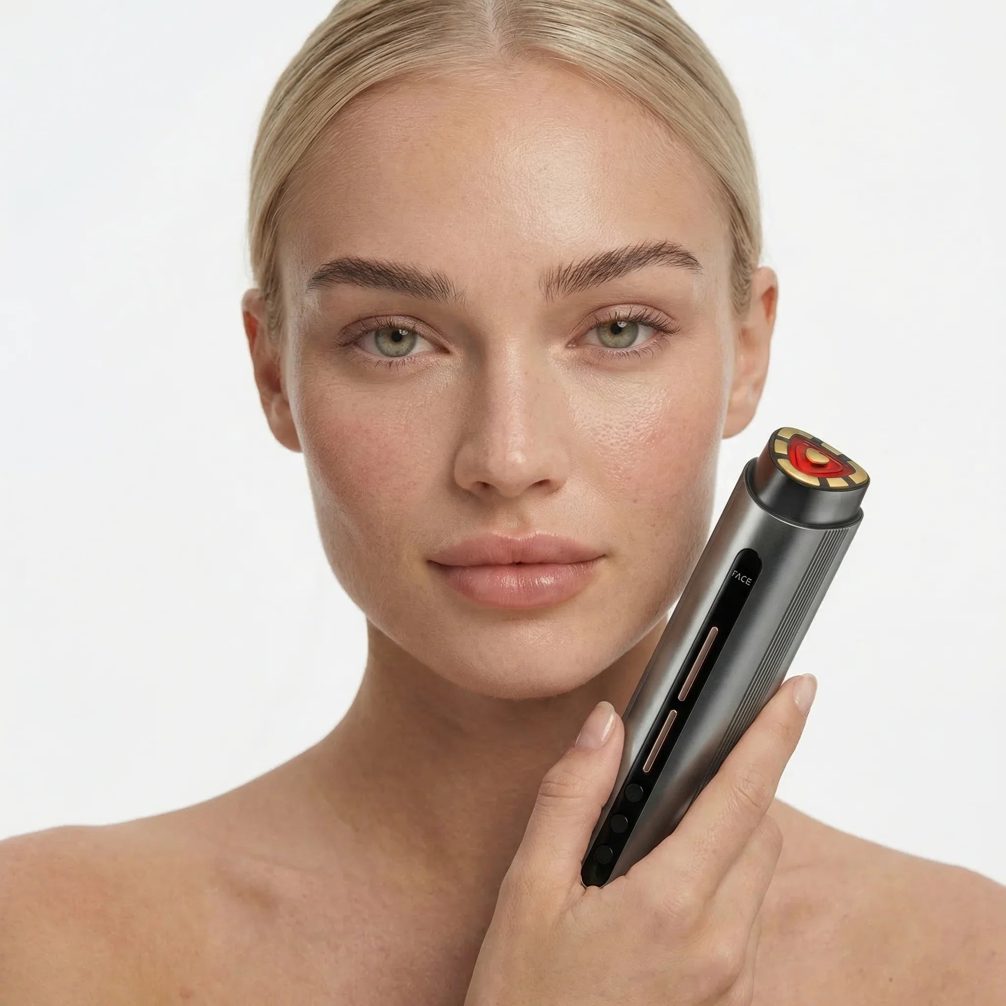Woman holding a facial red light device against a neutral background