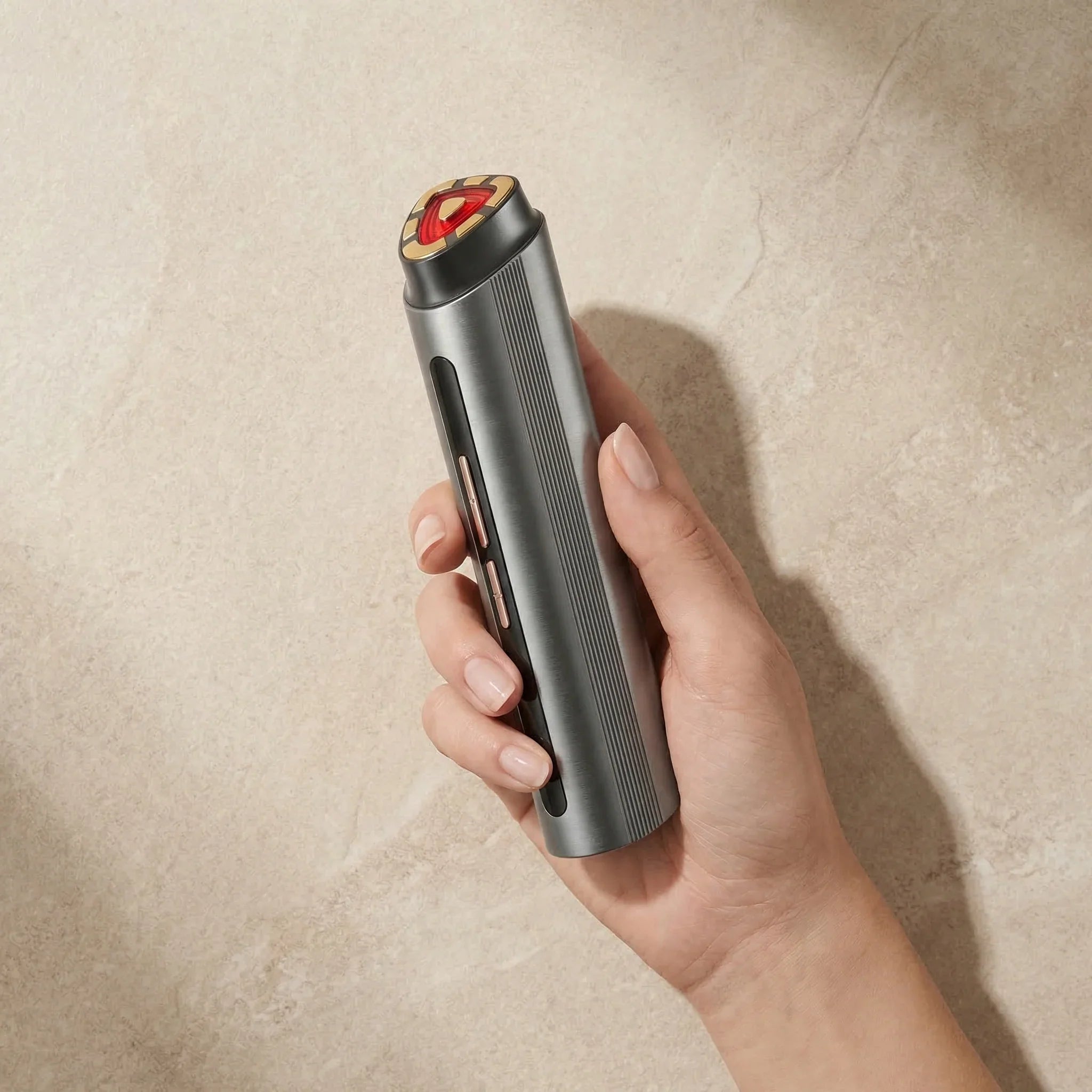 Hand holding a Nicebean facial red light cylindrical electronic device on a beige background