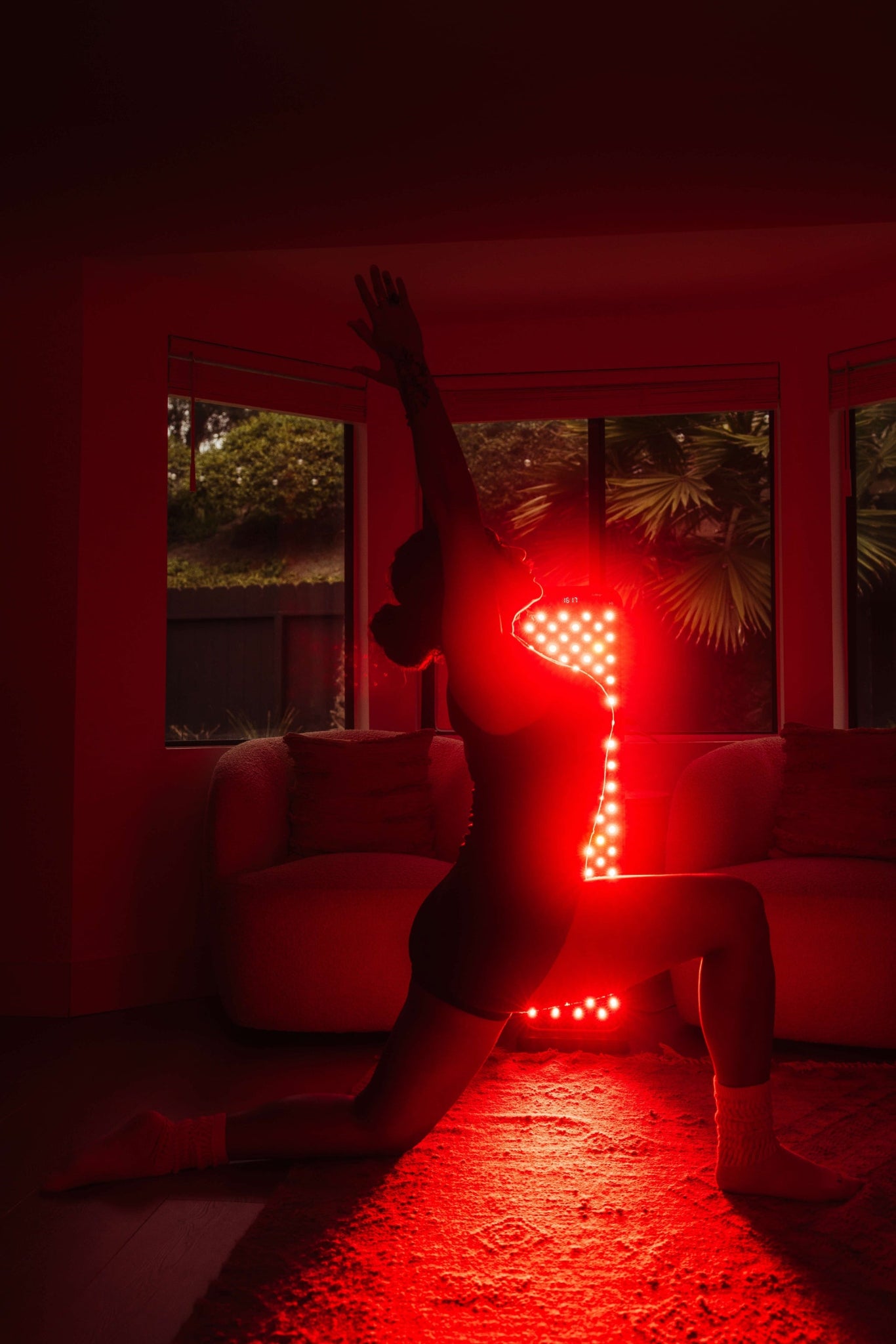Person in front of the red light panel in a dimly lit room.
