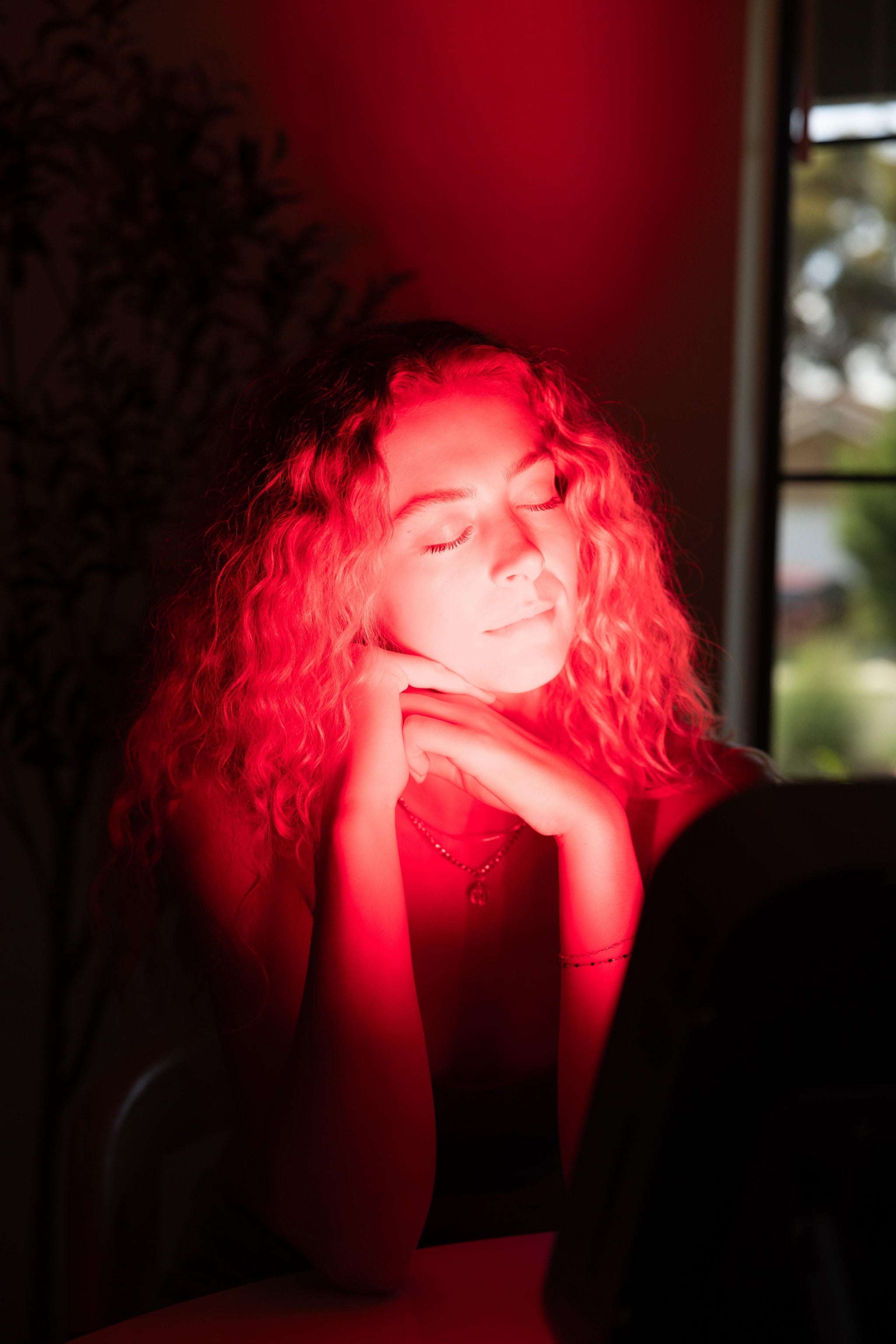 Woman using Renew Red Light Small Panel portable red light therapy device