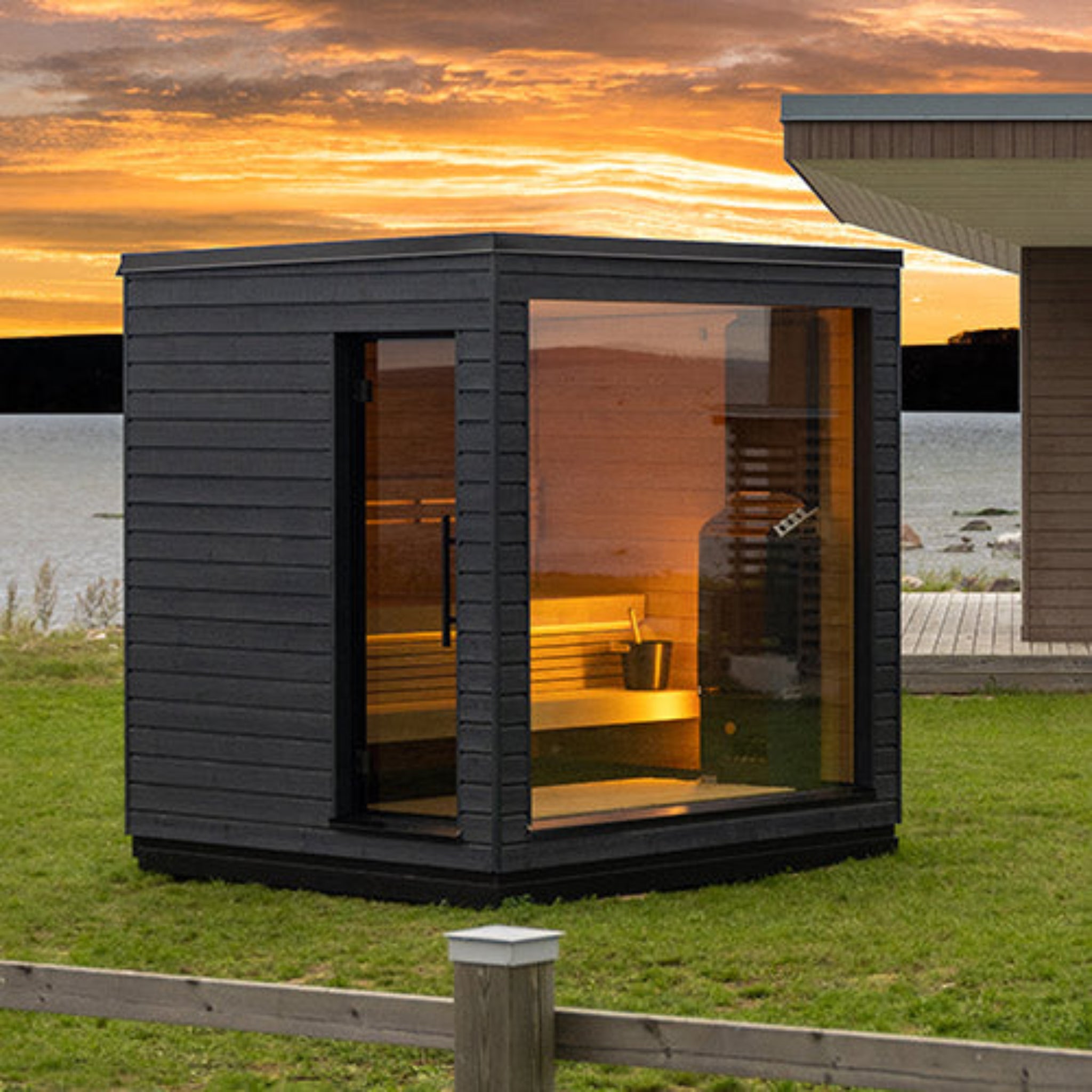 saunalife G6 sauna with a golden light in a backyard setting by a lake. angle view.