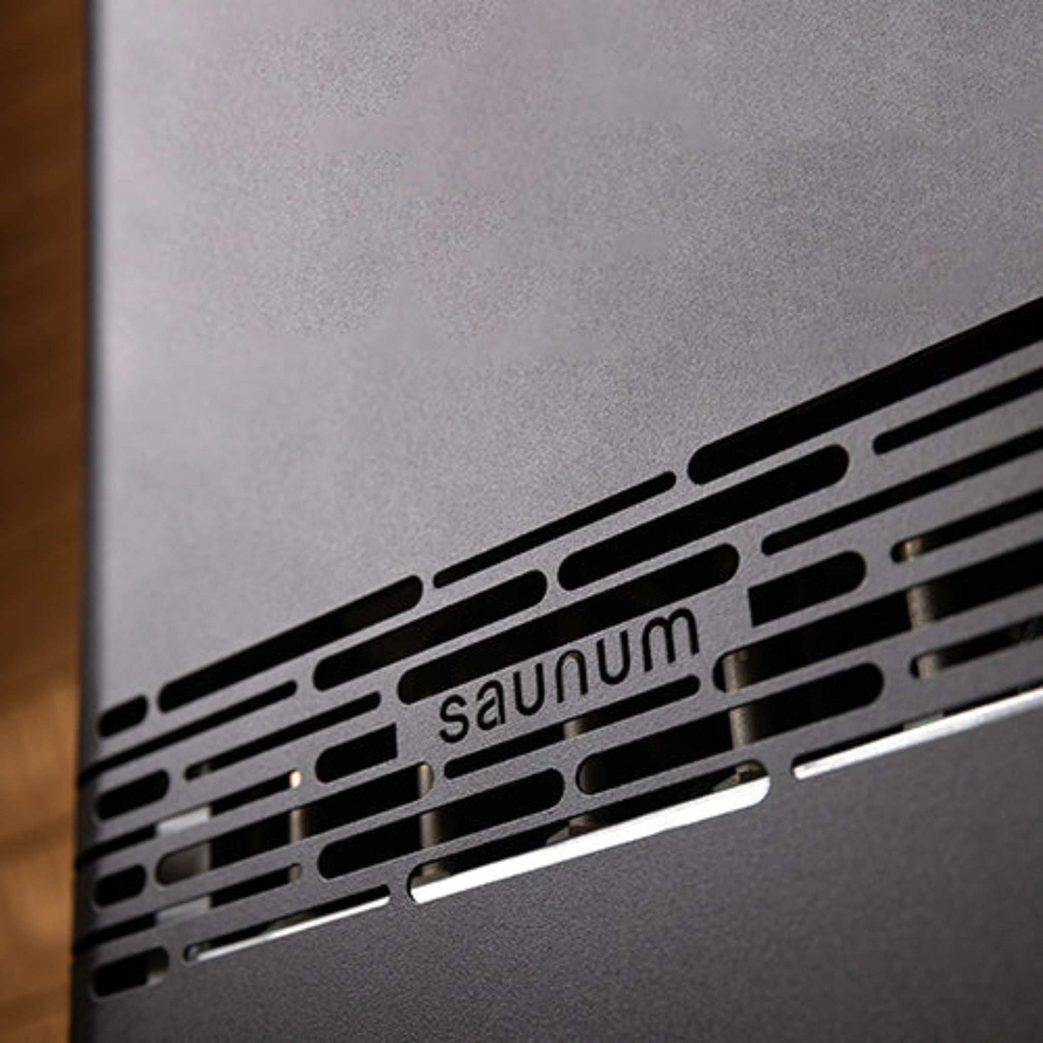 Close-up of a metallic surface with 'saunum' branding on a wooden background