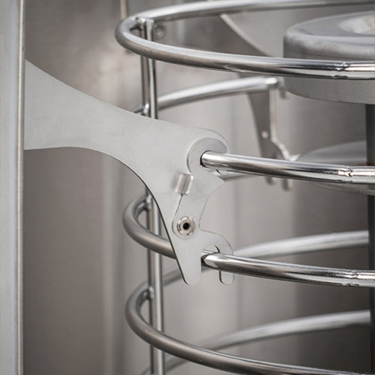 Close-up of a stainless steel spiral rack with the shield attachment support arm and visible fasteners.
