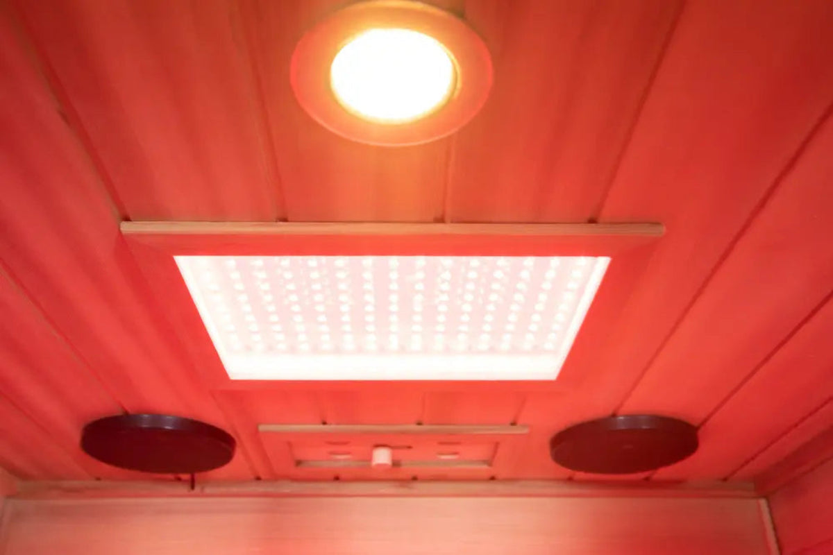 Interior view of the 1-person infrared sauna red cedar featuring overhead red light and speakers.