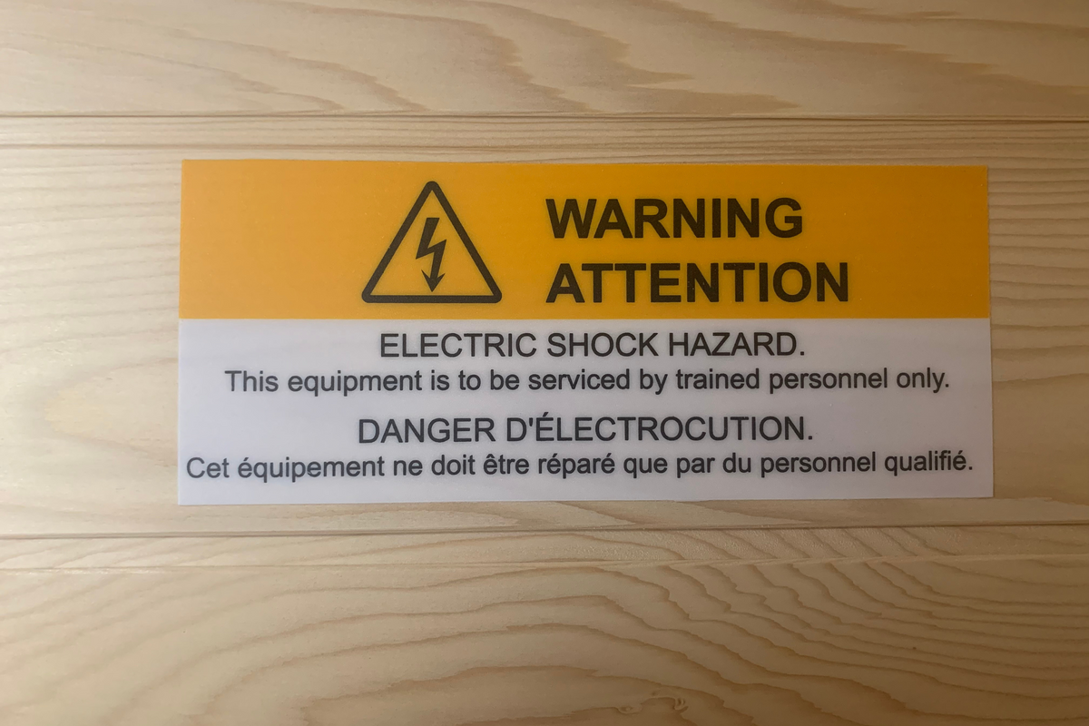 Warning label for electric shock hazard, indicating equipment is to be serviced by trained personnel only.