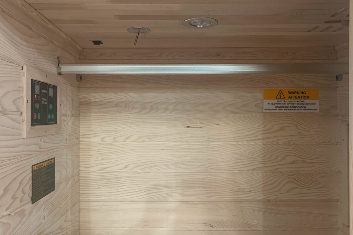Interior view of the Blisspod Vienna 1-Person Far Infrared Sauna with control panel and warning sign.