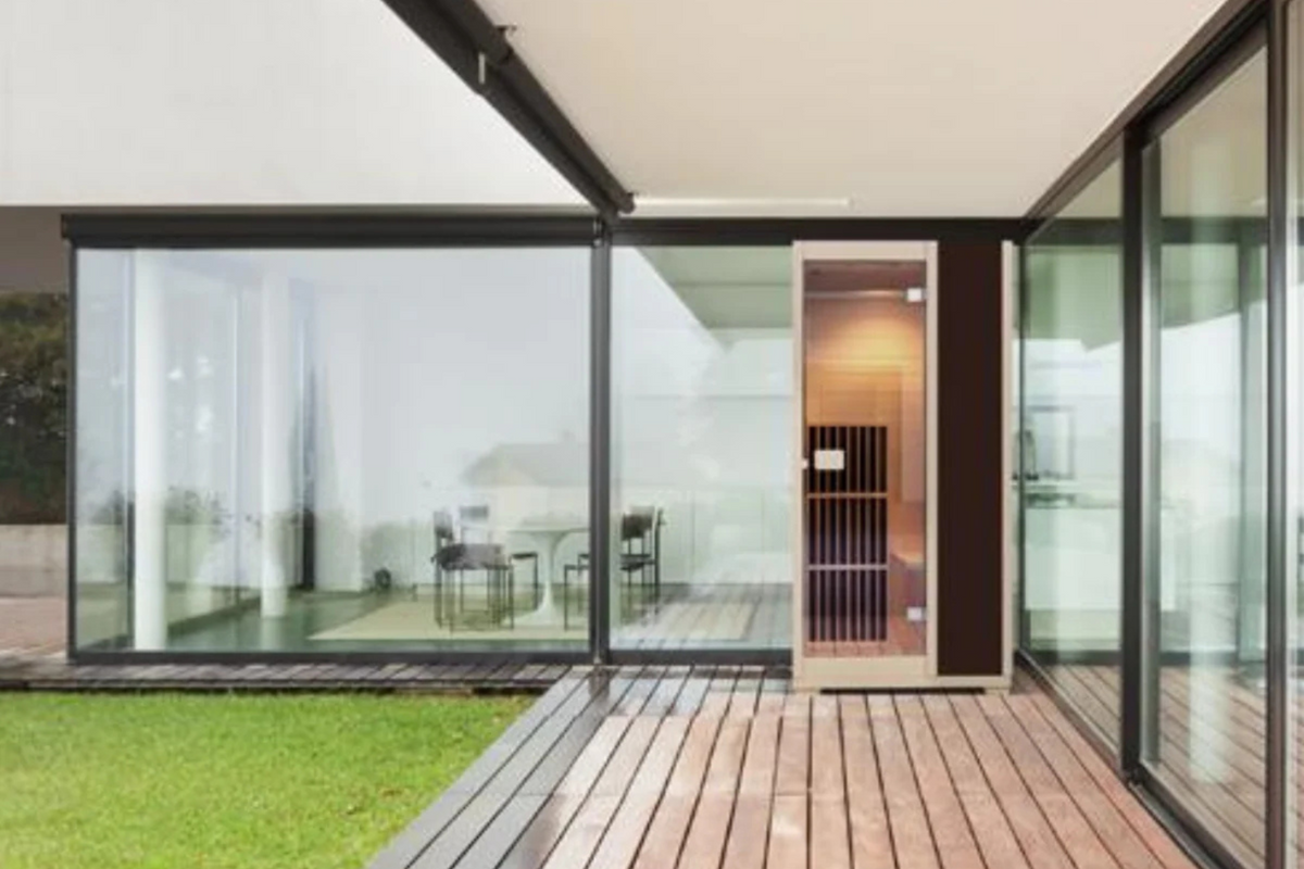 Blisspod Vienna 1-Person Far Infrared Sauna positioned outside a modern glass home, featuring Canadian Hemlock wood.