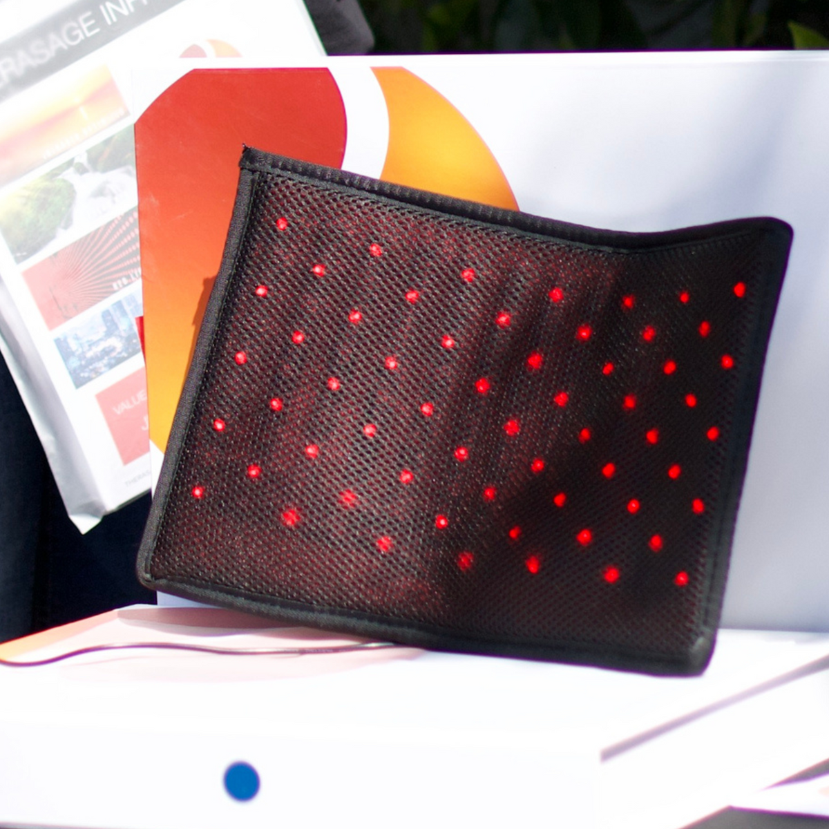 Therasage Tri-Lite™ Red Light Therapy Panel with red light dots on a mesh surface for home wellness.