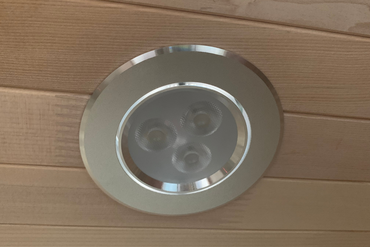 Ceiling light fixture in a far infrared sauna with wooden paneling.