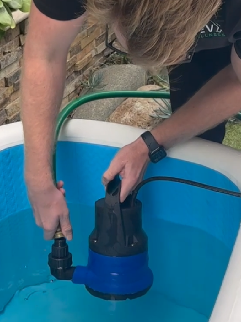 Person positioning the RevX drain pump in a tub
