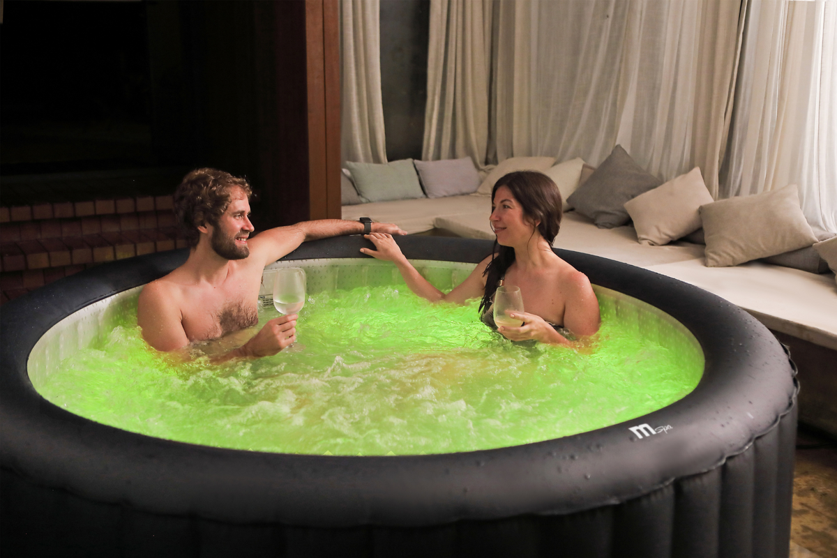 Two people in a hot tub with green water in a cozy room.