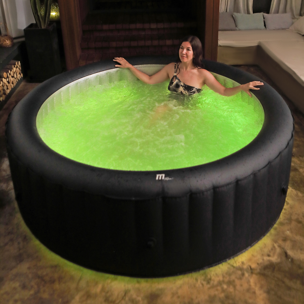 Woman in an inflatable hot tub with green water in a living room setting