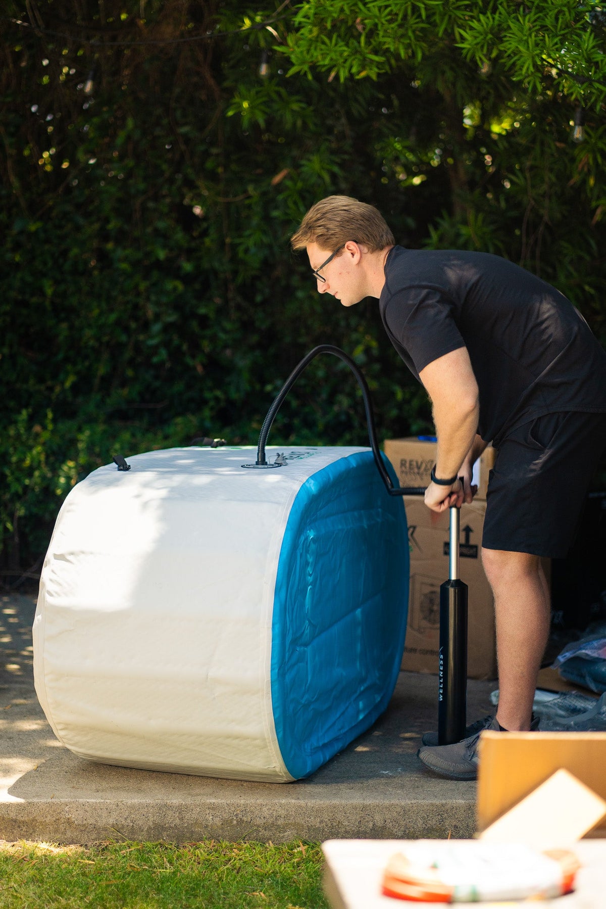 Person inflating a RevX inflatable tub with a manual pump
