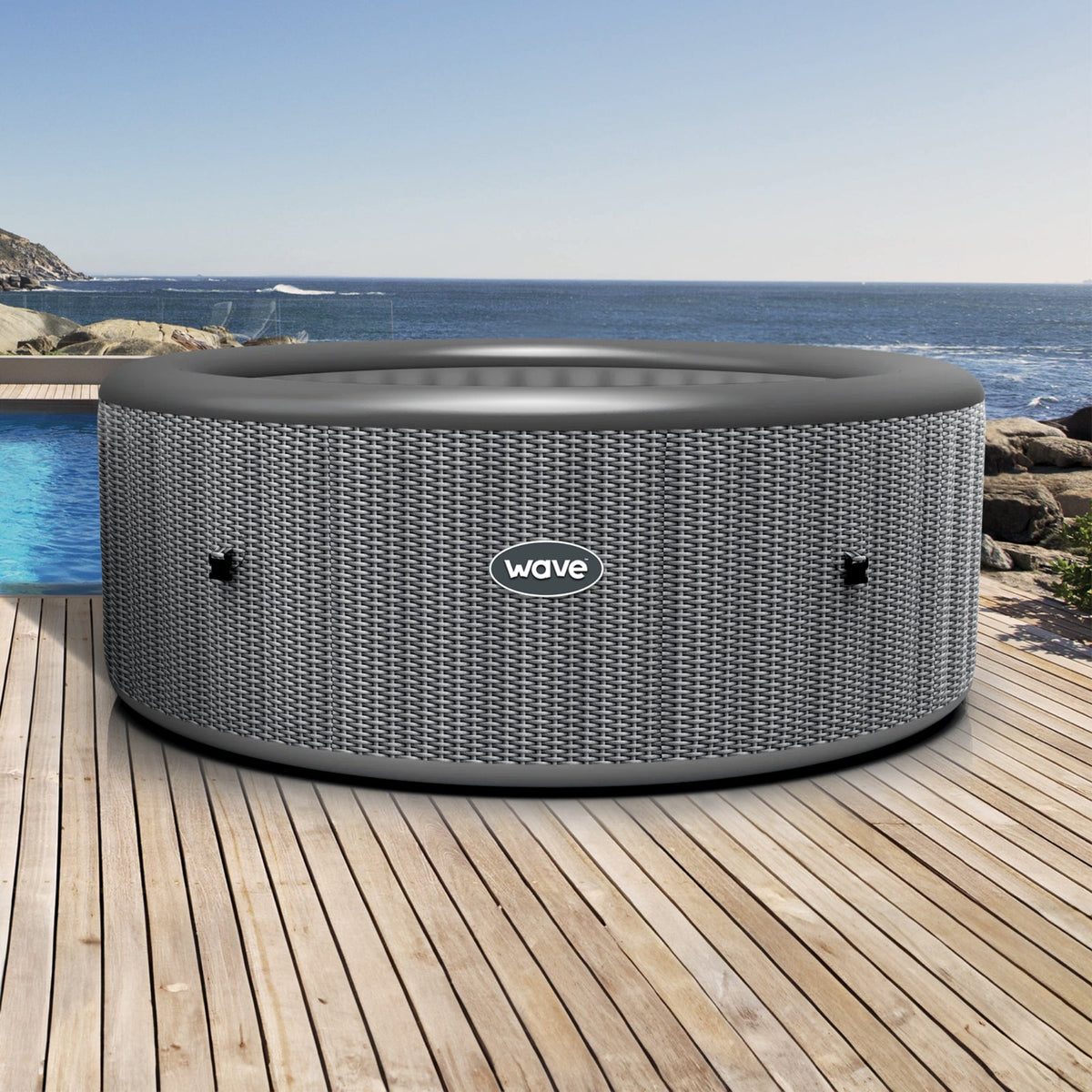 Atlantic Gray outdoor hot tub with 'Wave' branding on a wooden deck by the ocean.