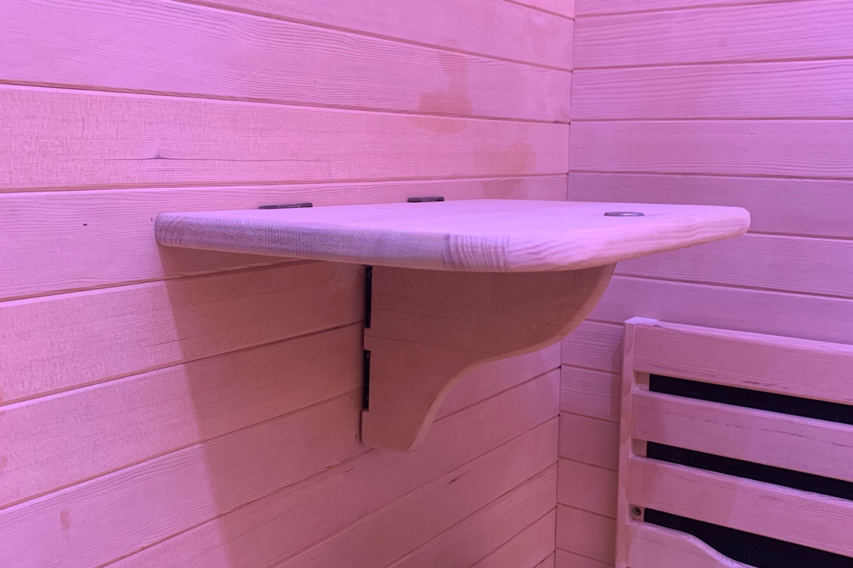 Full Spectrum Indoor Sauna wall-mounted wooden shelf in a pink-lit sauna interior.