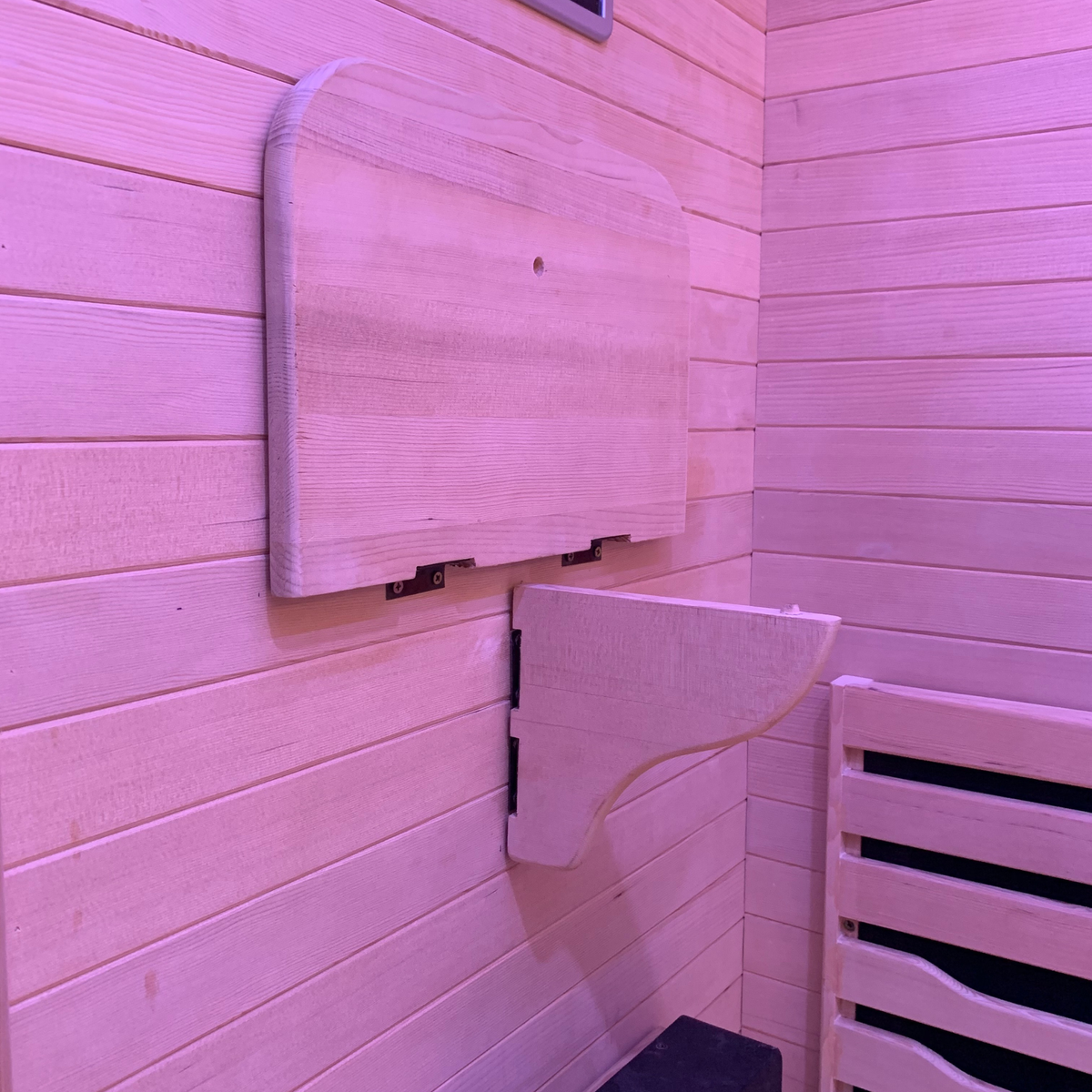 Full Spectrum Indoor Sauna interior wooden bench and wall features in soft pink lighting.