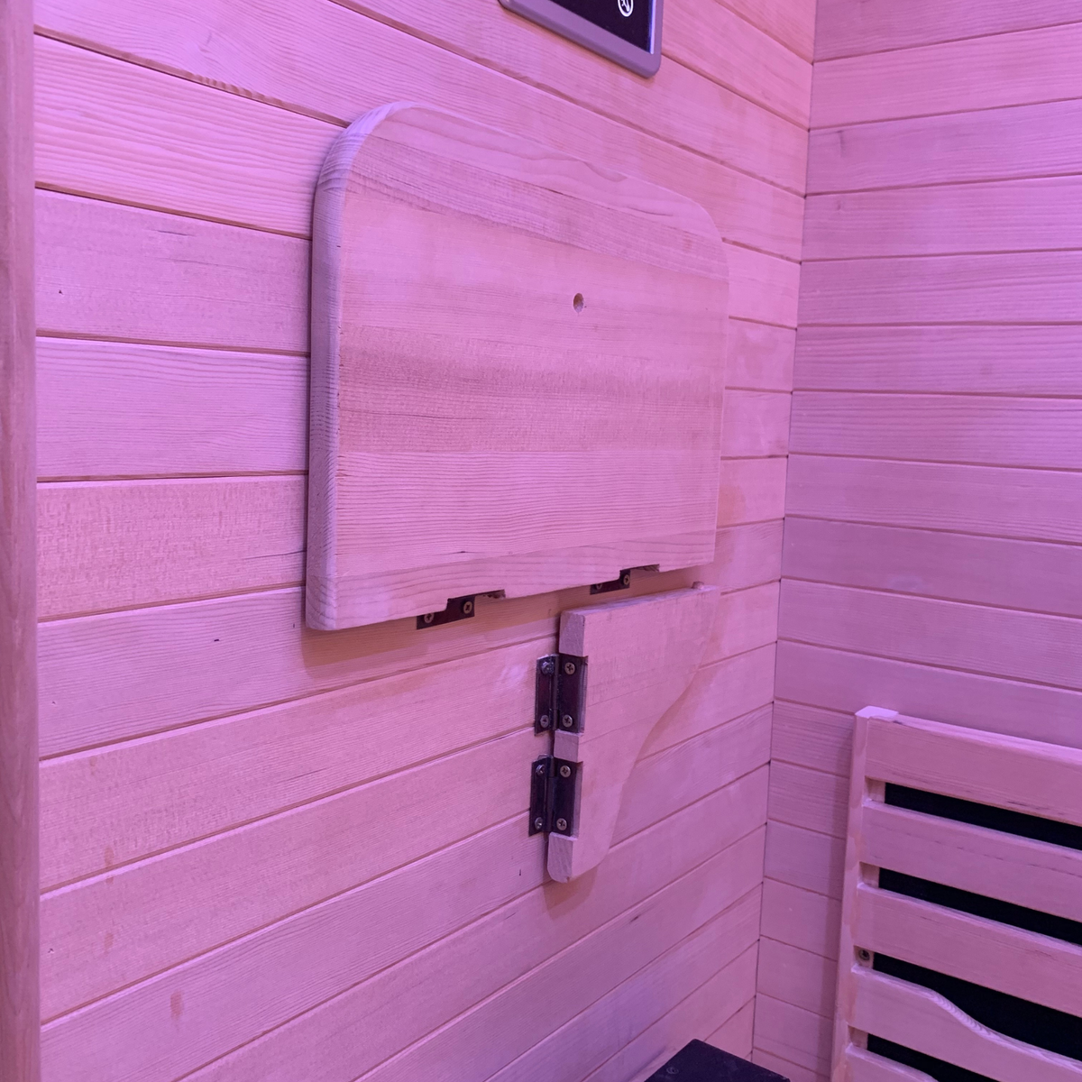 Full Spectrum Indoor Sauna interior with a wooden foldable shelf against the wall.