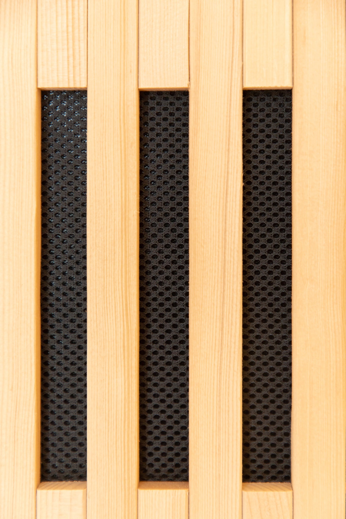 Wooden panel with black honeycomb pattern inside the Nicebeam Canadian Hemlock sauna