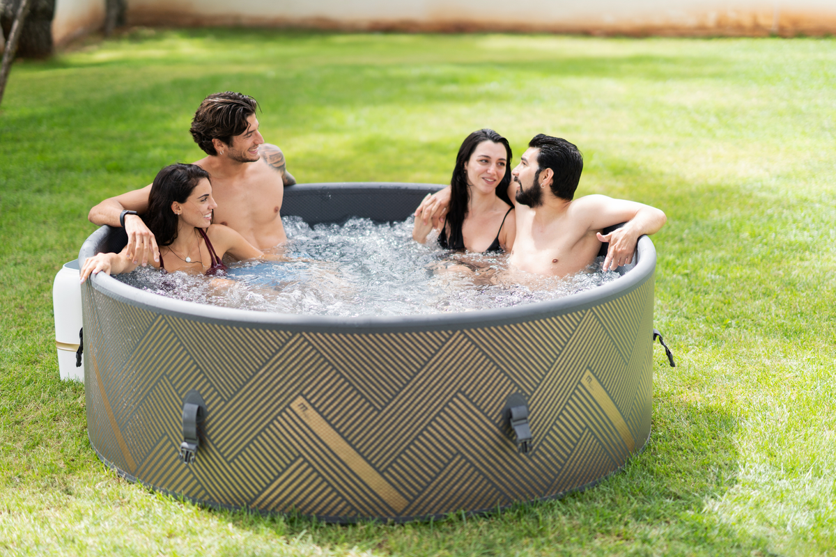 Group of four people enjoying a rigid hot tub in a grassy backyard, perfect for relaxation and social gatherings.
