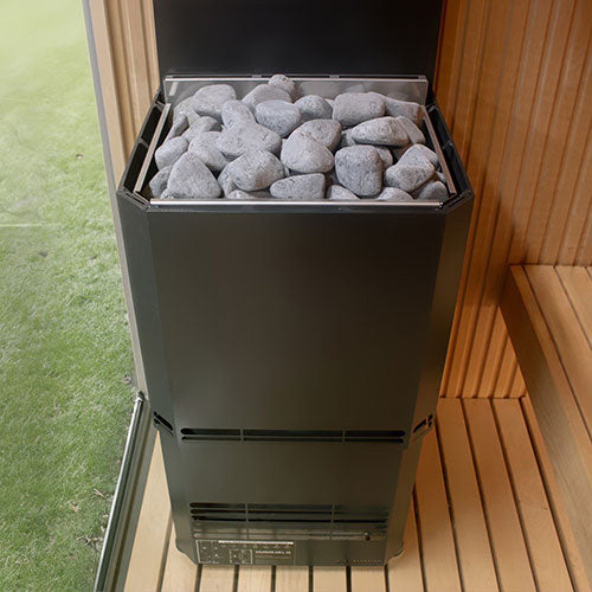 Saunum Air L Sauna Heater - Black by a sauna window in a backyard setting. front view