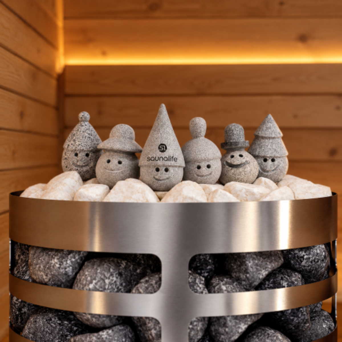A sauna stone set featuring six decorative gray stone snowman figures wearing different hats, arranged on white and dark gray sauna stones inside a stainless steel sauna sauna heater basket. The central hat is printed with the brand name 'saunalive'.