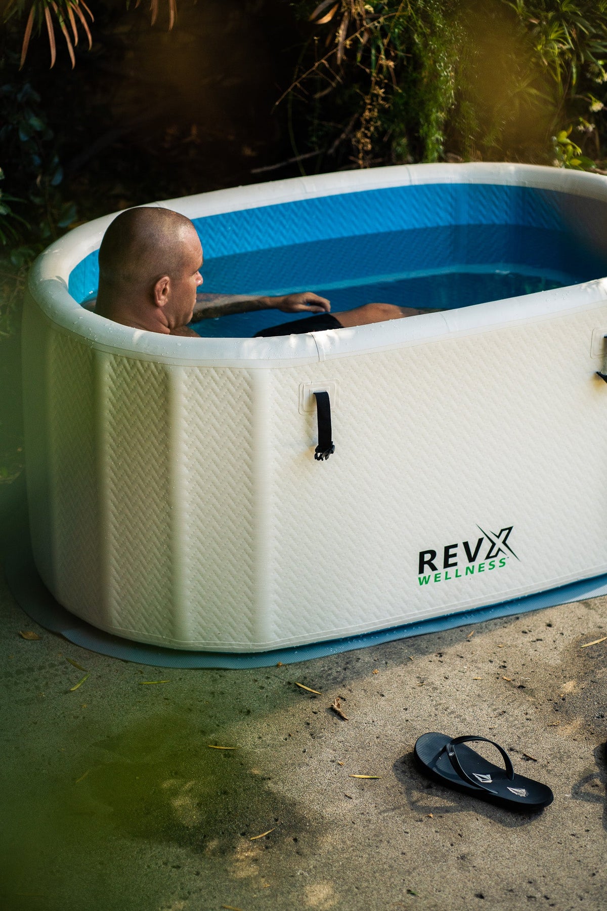 Person seated in a RevX inflatable cold plunge outdoors