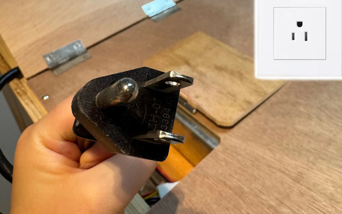 Close-up of a hand holding a power plug for a sauna, with a wall outlet in the background, demonstrating electrical connection.