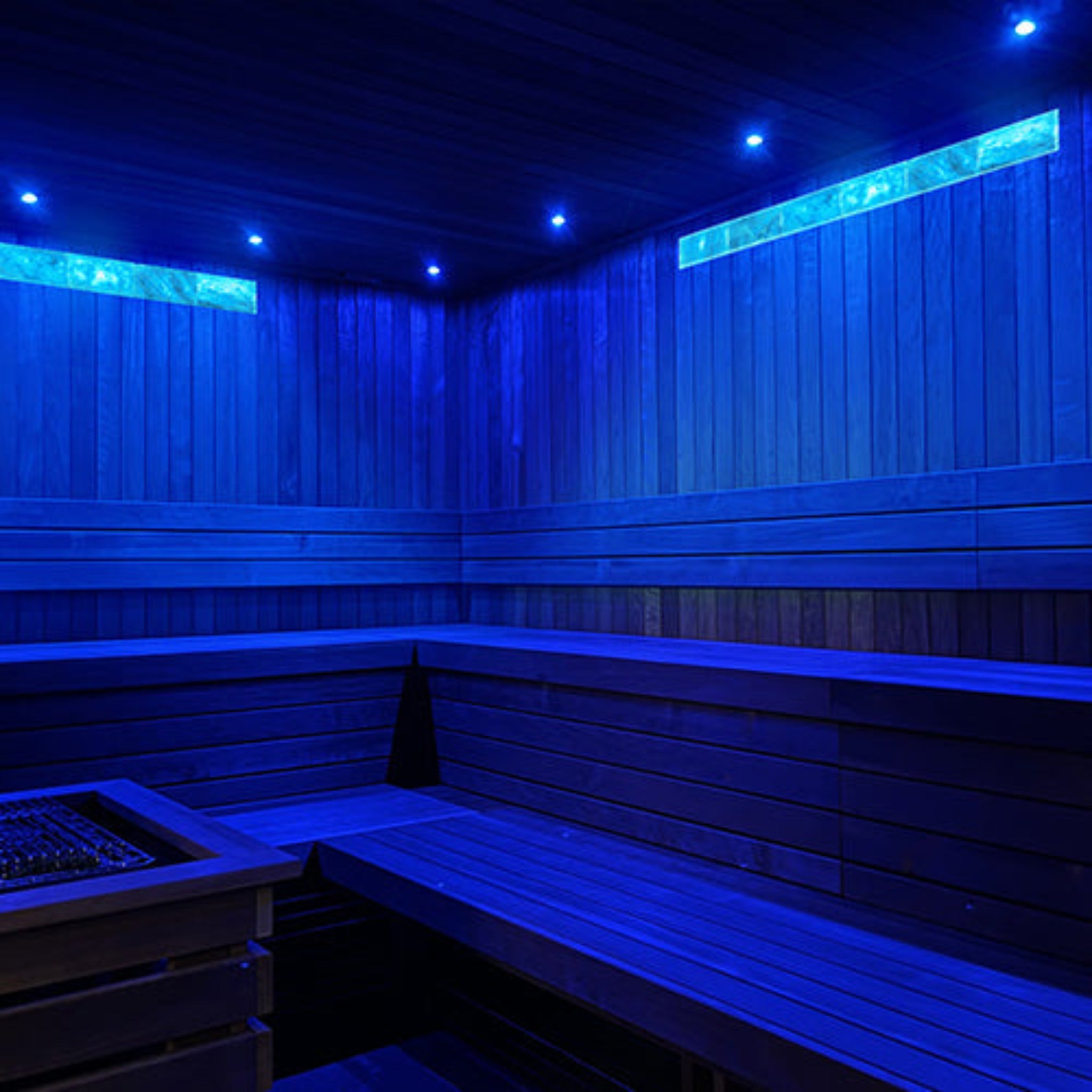 Blue-lit sauna with wooden benches and walls with PROSAUNAS Small Himalayan Salt Light Feature