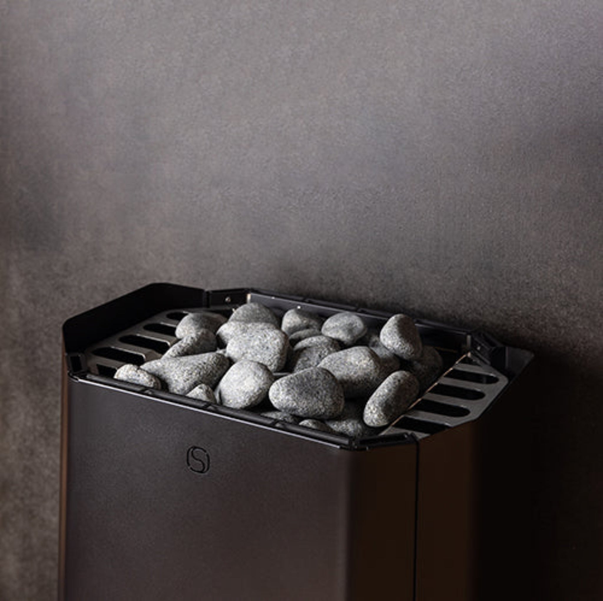 Black saunum air perfect sauna heater with stones against a dark wall.